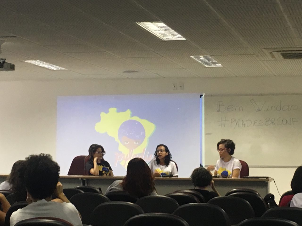 picture of PyLadiesBRConf. Three women sitting in front of a table, on stage, speaking