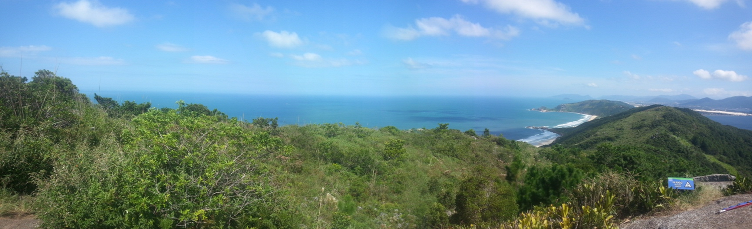 Photo taken from the top of a hill, overlooking light green ocean beaches